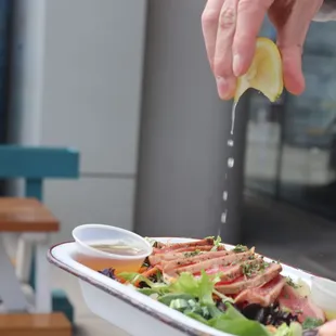 a person squeezing a lemon over a salad