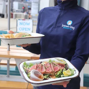 a woman holding two plates of food