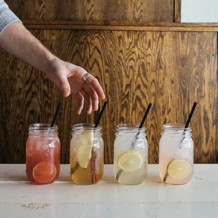 a person placing lemon slices in mason jars