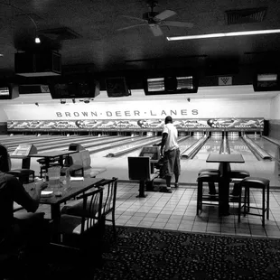 a bowling alley with people sitting at tables