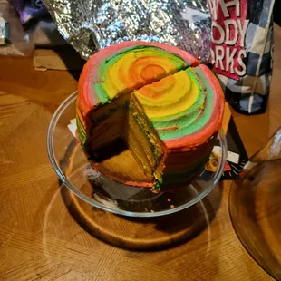 a rainbow cake with a slice taken out of it