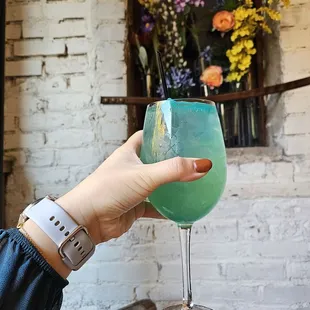 a hand holding a glass of blue liquid