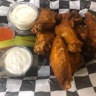a basket of chicken wings and dips
