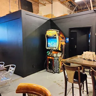 a room with a table, chairs, and an arcade machine