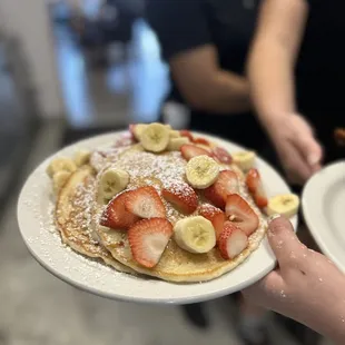 a plate of pancakes with strawberries and bananas