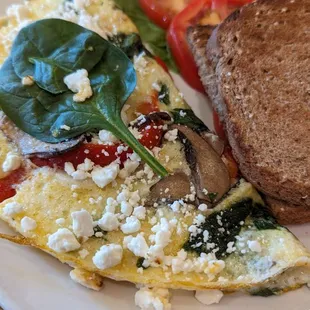 an omelet with spinach, tomatoes, mushrooms, and a slice of