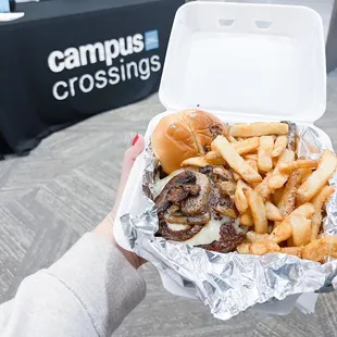 a person holding a container of fries