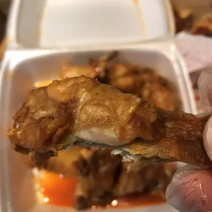 a hand holding a piece of chicken