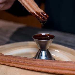 a person dipping chocolate into a sauce