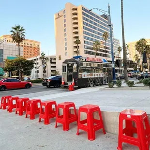 a row of red stools in front of a food truck