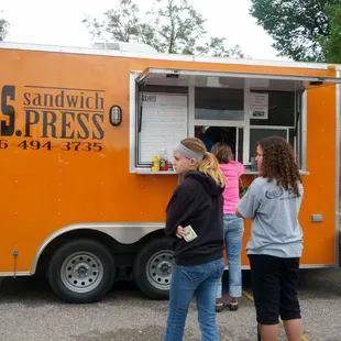 three people standing in front of a food truck