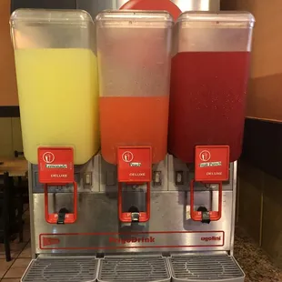 three juice dispensers on a counter