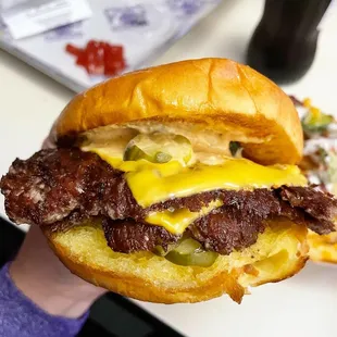 a hand holding a cheeseburger