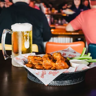 a basket of chicken wings and a glass of beer