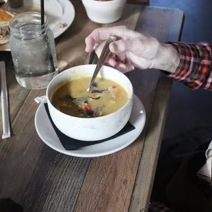 a person holding a spoon over a bowl of soup