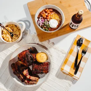 a plate of ribs, beans, coleslaw, and macaroni and cheese