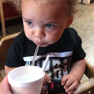 a toddler drinking from a paper cup