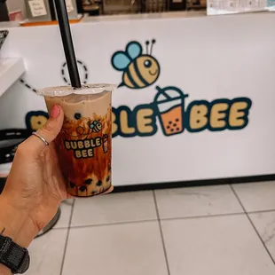 a hand holding a cup of bubble bee