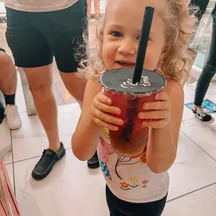 a little girl holding a drink
