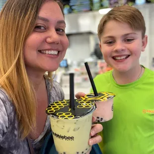 a woman and a boy holding a bubble tea