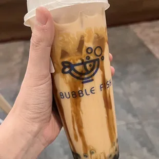 a hand holding a cup of bubble fish