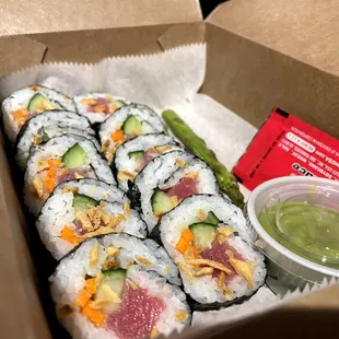 a box of sushi rolls with a dipping sauce