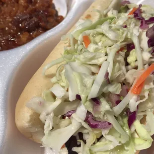 a hot dog with coleslaw and beans