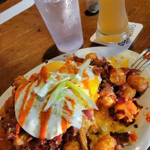 Wake &amp; Bake Tots: crumbled andouille, applewood smoked bacon bits, beer cheese, sunny egg, sriracha, scallions.