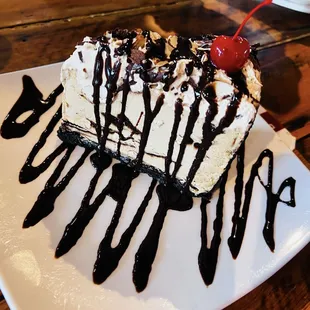 Mudd Pie: Mocha almond fudge ice cream cake in a cookie crust topped with a chocolate drizzle, sliced almonds, whipped cream, and a cherry