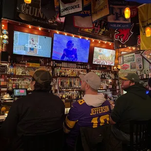 two men sitting at a bar watching a football game