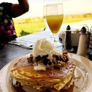 a plate of pancakes with whipped cream and syrup