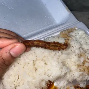 a hand grabbing a piece of rice with a fork