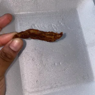 a piece of bacon in a styrofoam container