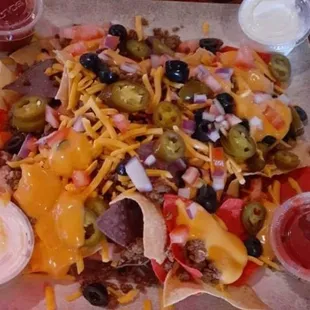 a nachos with cheese, olives, and other toppings