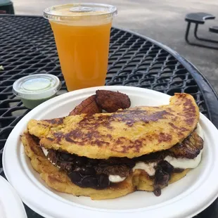 Cachapa filled with cheese, shredded beef, black beans and served with plantains. Passion fruit juice. Delicious.
