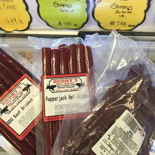 a hand holding a package of pepper jack hot dogs