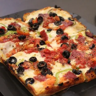 a square pizza with olives and pepperoni