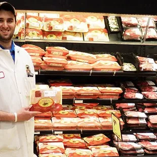 a man standing in front of a display of meat