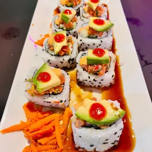a plate of sushi with carrots and avocado