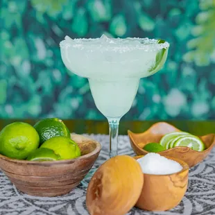 a margarita and limes on a table