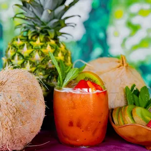 a pineapple, strawberries, and a cocktail