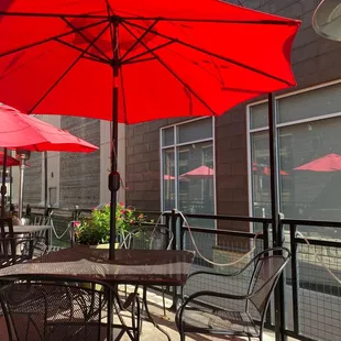 tables and chairs with red umbrellas