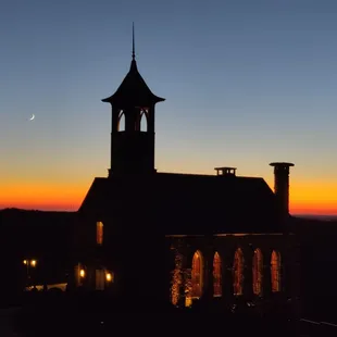 a silhouette of a church at sunset