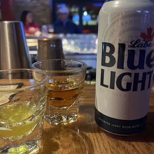 a can of blue light next to a shot of whiskey