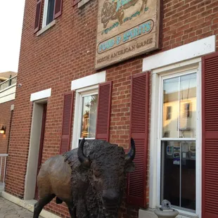 a statue of a buffalo in front of a brick building