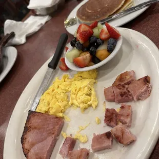 Two eggs with ham, fruit and pancakes