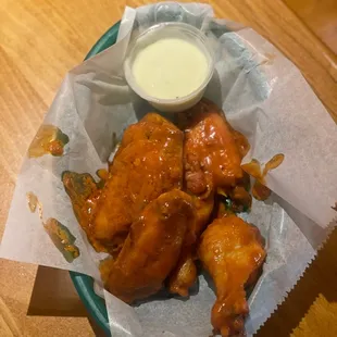 a basket of buffalo wings with a side of ranch dressing
