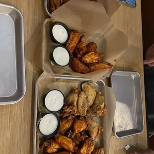 two trays of buffalo wings with dips