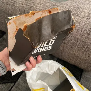 a hand holding a box of buffalo wild wings