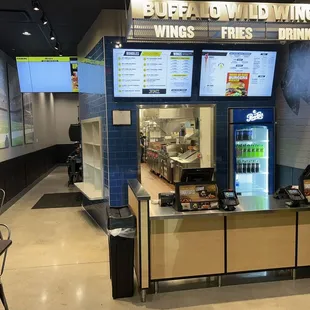 Ordering desk near entrance, pickup cubby holes on the left, white shelving.